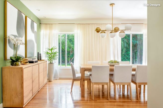 dining room with light wood furniture and green accent wall